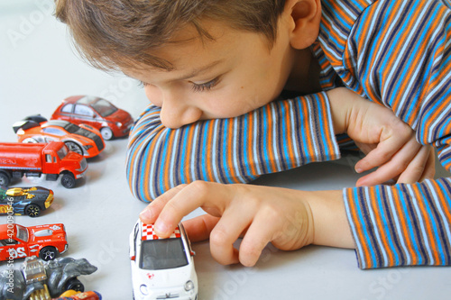 BAMBINO GIOCANDO CON AUTOMOBILI GIOCATTOLO SUL PAVIMENTO