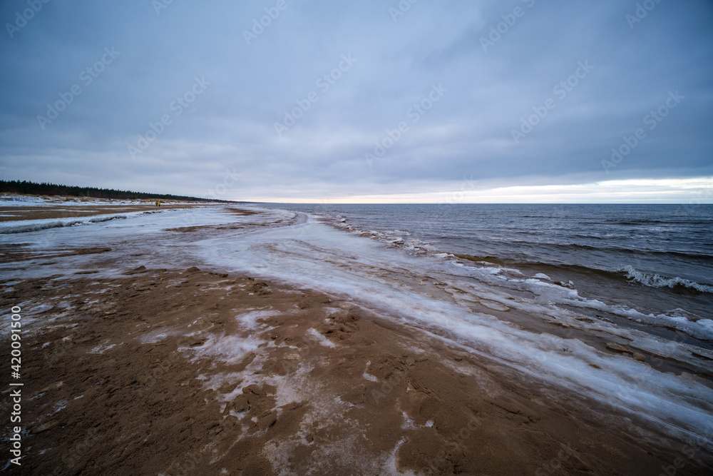 icy winter beach near the sea with frozen sand and ice blocks in the water