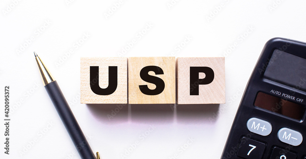 The words USP Unique Selling Proposition is written on wooden cubes between a pen and a calculator on a light background. The words USP Unique Selling Proposition is written on wooden cubes between a pen and a calculator on a light background.