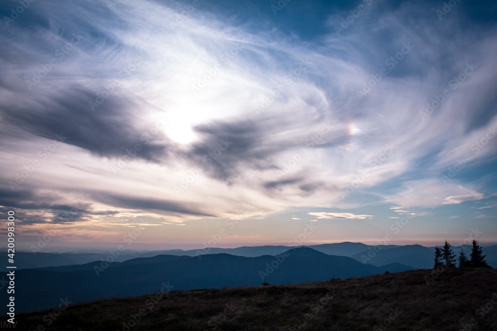 Halo natural phenomenon through clouds. Mountain Landscape view in windy weather.