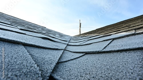 time lapse video of frost melting from a residential shingle roof as the sun rises in the morning