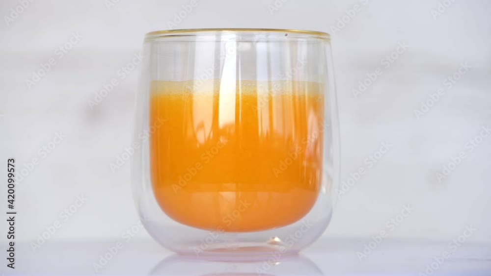 Spinning transparent glass of orange fresh juice