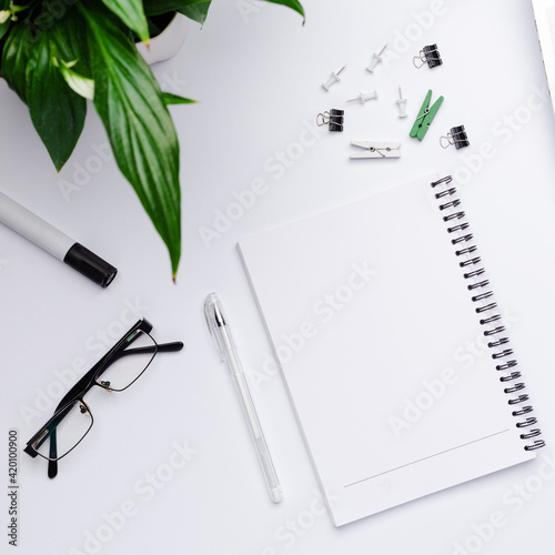 Top view on working space with a white notebook with free space for text in the center. A designer workplace with stationery items and colorful stuff.