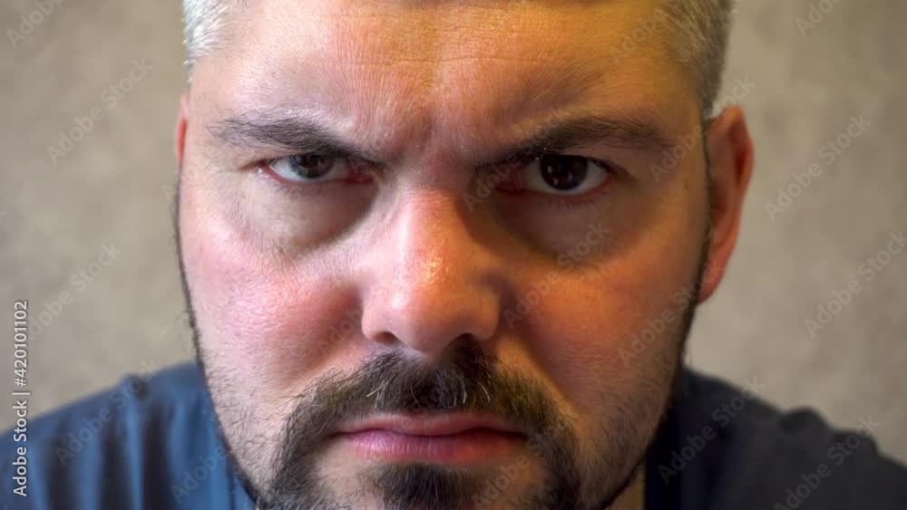 Gloomy man. Bearded face. Grimaces. Winks an eye. Nervous person. Dark hair. European type of face. Part of the head. Close-up. Gloomy man. Bearded face. Grimaces. Winks an eye. Nervous person. Dark hair. European type of face. Part of the head. Close-up.