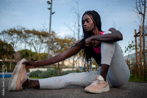 Front view of a black woman streching her legs. outdoors exercise, fitness routine