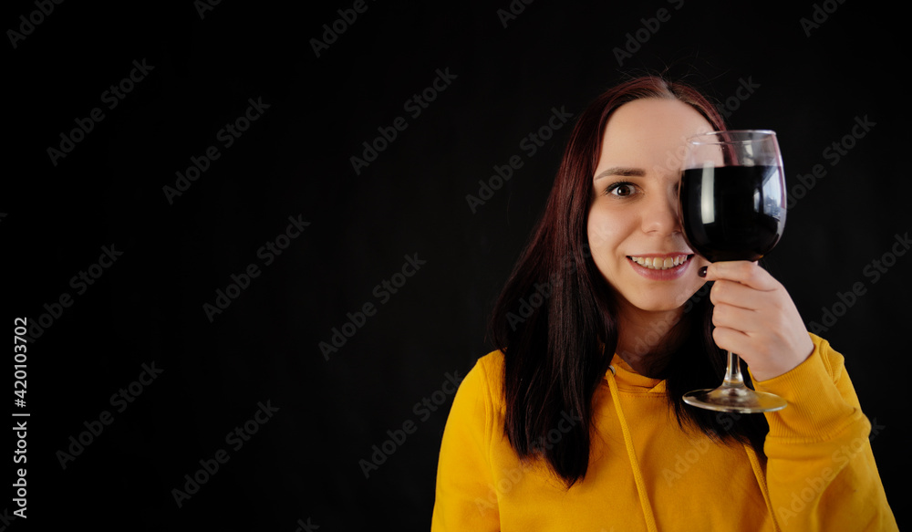 Relaxed young woman poses with glass of red wine on black background. Adult happy brunette resting with alcohol in her weekend. Relaxed young woman poses with glass of red wine on black background. Adult happy brunette resting with alcohol in her weekend.