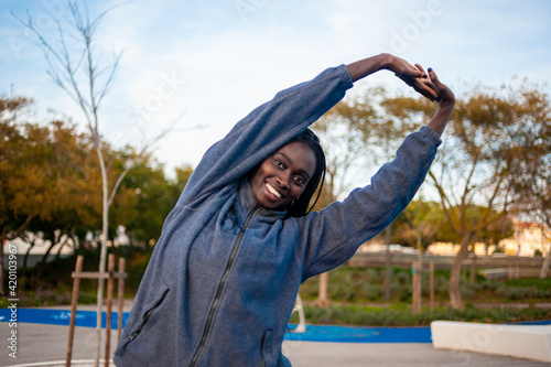 smiling black woman streching her arms exercising outside. great copy space.
