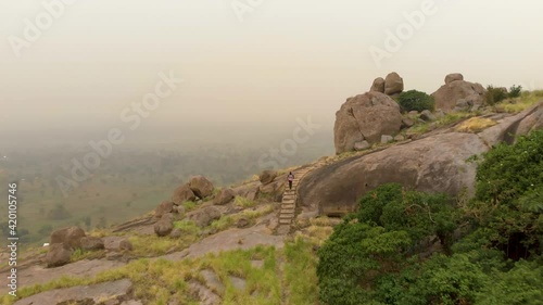 Aerial shot following an African man running up a stair case on a granite mountain in Africa. photo