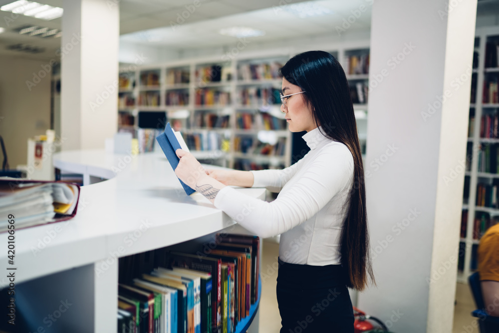 Woman reading book at library counter Woman reading book at library counter