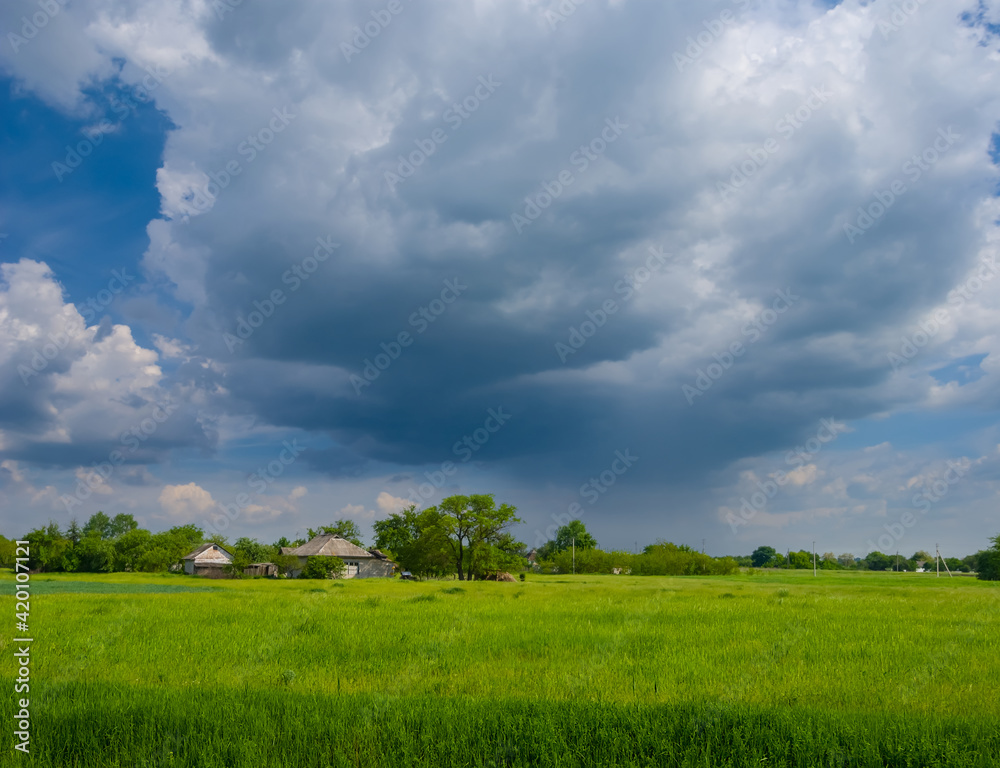 small farm among green fields under a dense rainy clouds small farm among green fields under a dense rainy clouds