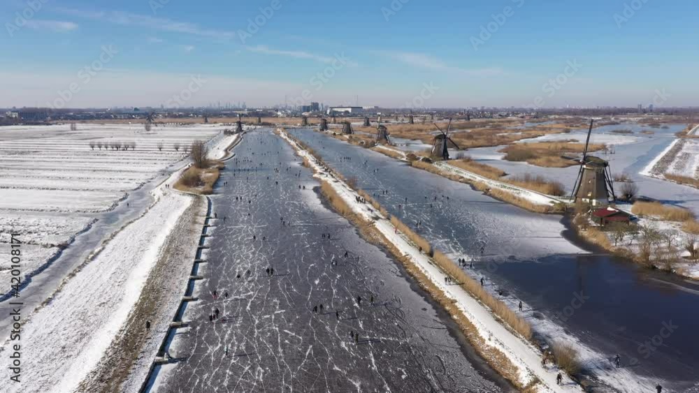 Classic Dutch Winter landscape, bird's eye perspective. Drone flight of people having fun and ice skating in typical Dutch landscape of windmills.
Classic Dutch Winter landscape, bird's eye perspective. Drone flight of people having fun and ice skating in typical Dutch landscape of windmills.
