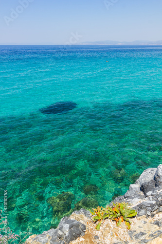 Vertical view of the turquoise waters of the Aegean Sea. Wild clifs in front of turquoise water. Summer vacation by the sea