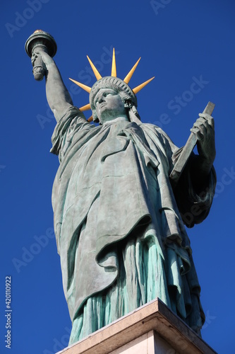 Statue de la Liberté, réplique de la célèbre statue de New York City (USA), au bout de l'allée des cygnes, sur l’île aux cygnes à Paris, vue en contre-plongée sur fond de ciel bleu (France) photo