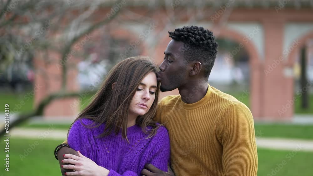 Boyfriend consoling sad girlfriend. Interracial couple, kissing forehead calming depression Boyfriend consoling sad girlfriend. Interracial couple, kissing forehead calming depression