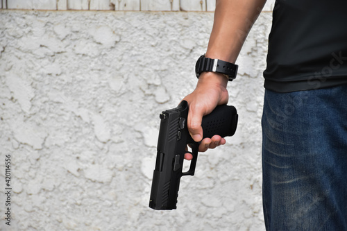 Automatic black pistol holding in hands.