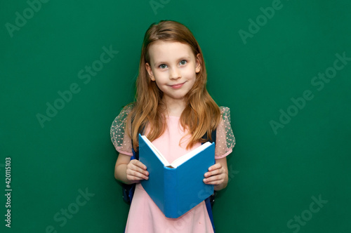 Child girl with a schoolbag and books in hands