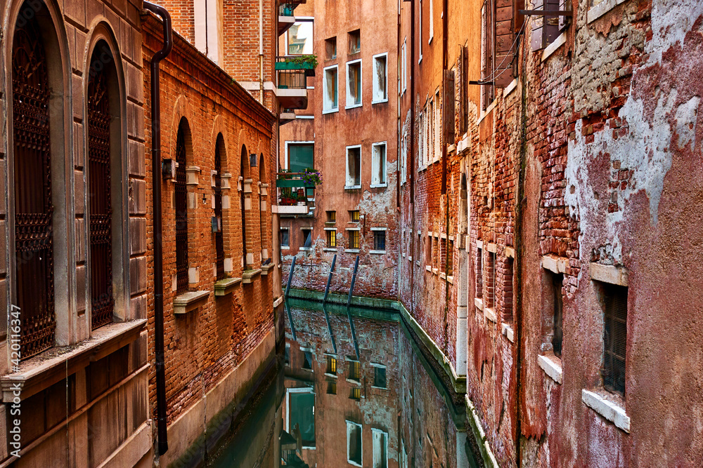 Narrow canal between rows of old buildings in Venice