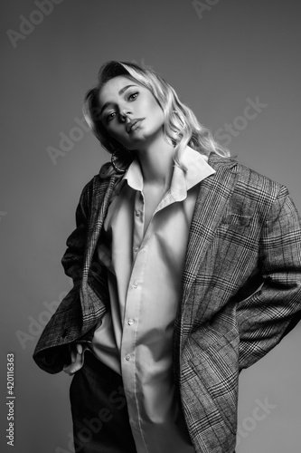 blonde fashionable woman in men's suit standing in black and white