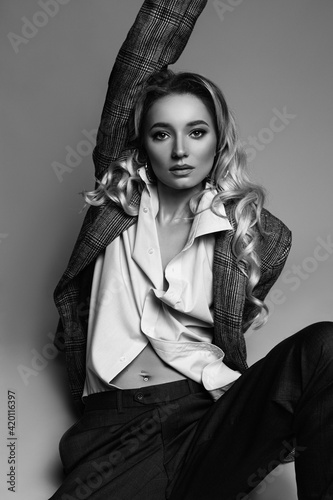 a blonde woman in suit sitting on the floor and holds a hand