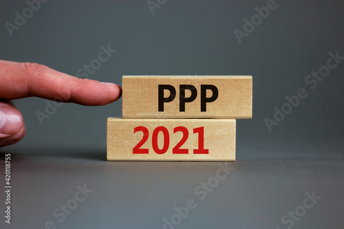 PPP, paycheck protection program 2021 symbol. Concept words PPP, paycheck protection program 2021 on wooden blocks on a beautiful grey backgrounds. Businessman hand. Business, PPP 2021 concept.