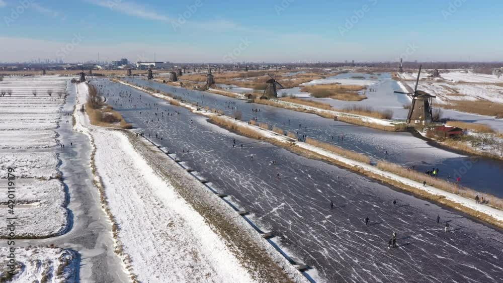 Drone flight over classic Winter landscape in the Netherlands. People ice skate on frozen canals past windmills, enjoying a traditional Dutch sport (a welcome break from Covid-19 lockdown)
Drone flight over classic Winter landscape in the Netherlands. People ice skate on frozen canals past windmills, enjoying a traditional Dutch sport (a welcome break from Covid-19 lockdown)