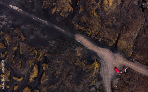 Icelandic road from a drone point of view, top down, with a red car at the end of the road