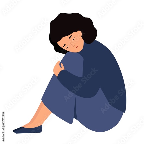 A pensive girl sits with her head on her knees. A woman is sad alone.