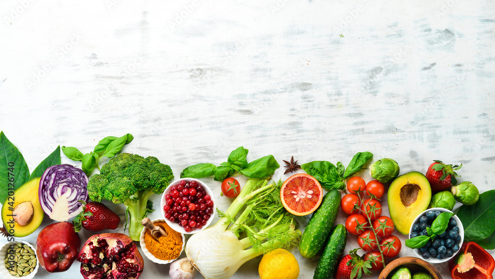 Healthy organic food: fresh vegetables and fruits on a white wooden background. Free space for your text.