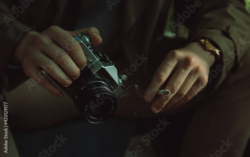 Young man with black and silver retro camera smoking a cigarette