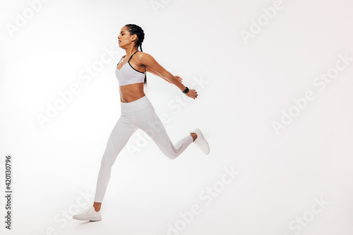 Young mixed race woman running over white background in studio