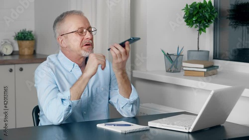 An elderly person is talking on the speakerphone of a mobile phone.