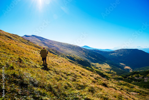 Back view of man backpack hiking on green mountains