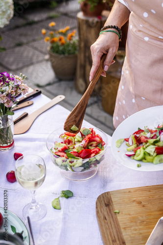 Woman serving fresh vegetable salad outdoors. Healthy vegetarian food on banquet and garden party photo