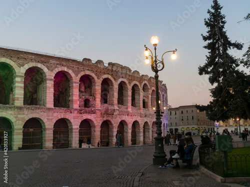 Arena di Verona, the ancient Roman amphitheatre. The evening view with the monument illuminated and coloured by green, red and blue lights. Verona, Italy - March 2021.