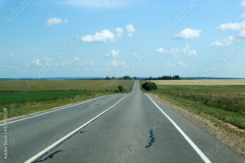 asphalt road in the countryside surrounded by field, russian outback