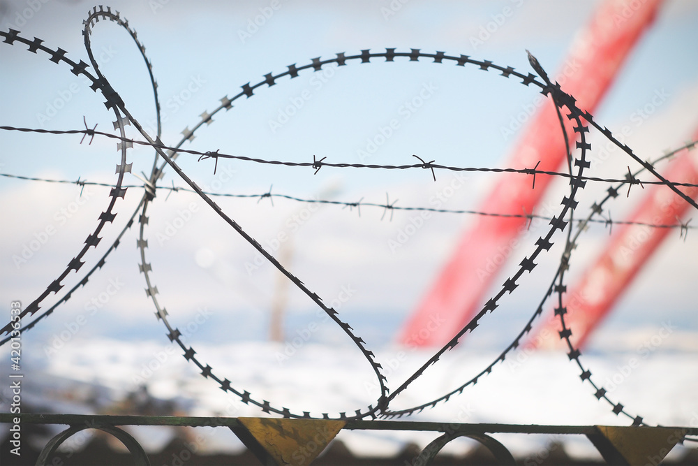 Barbed wire over the fence on a blurred background Barbed wire over the fence on a blurred background