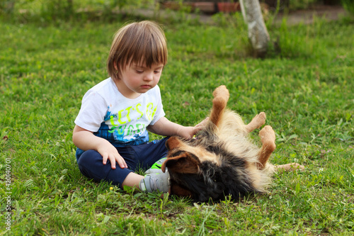 cute boy with down syndorme playing with his dog. Best friends, concept.