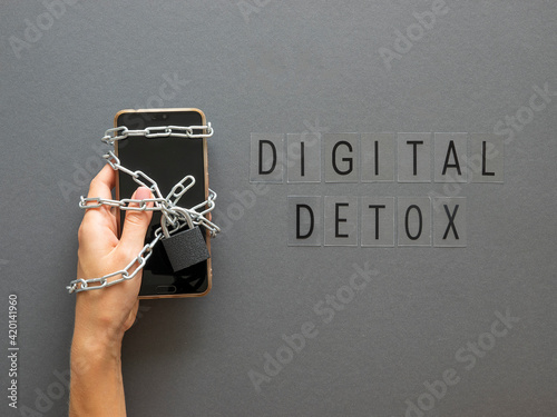 Hand hold locked with chain and lock smartphone. Digital detox words, top view photo