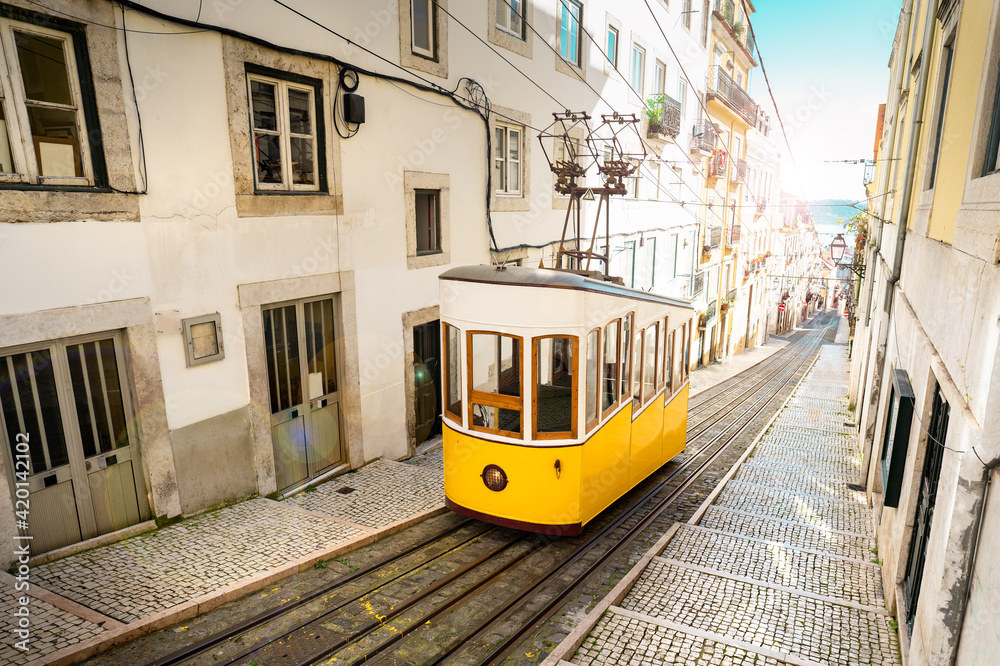 Fototapeta premium Lisbon city old town narrow streets and tram, Portugal. Famous retro yellow funicular tram on a sunny summer day