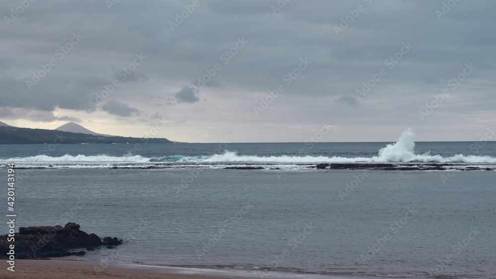 Big powerful waves at the beach hit breakwater. Winter season, windy and stormy weather. 