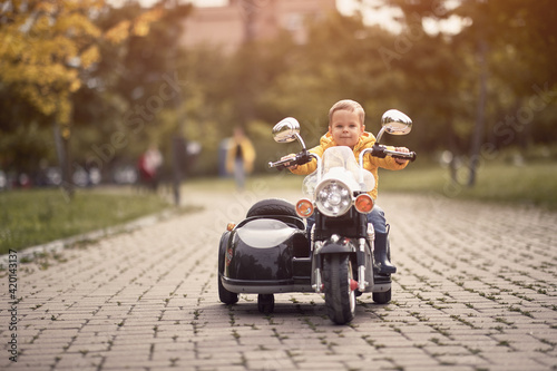 caucasian toddler driving replica of motorcycle outdoor