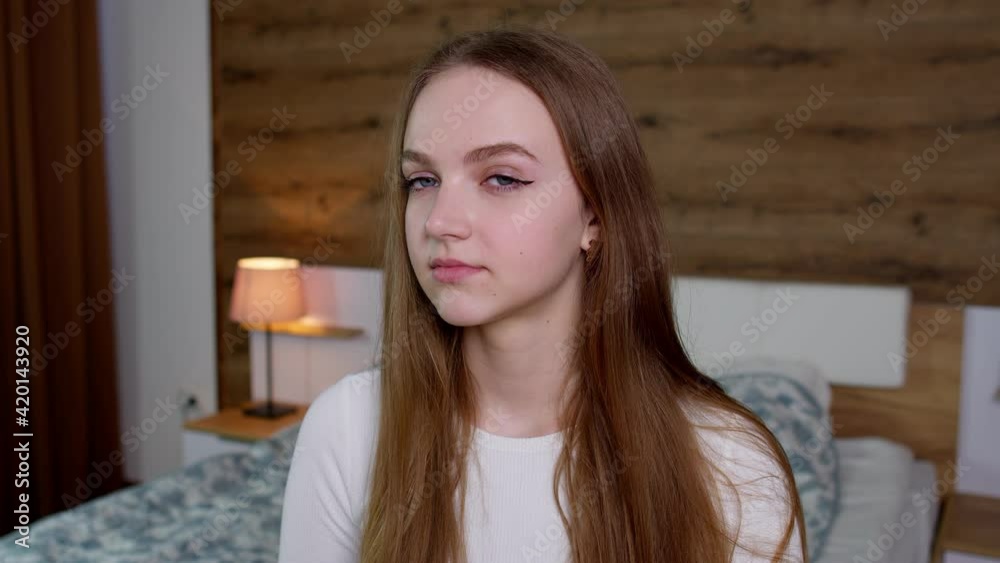 Smiling pretty young woman in good mood looking at camera, smiles gently on bedroom background Smiling pretty young woman in good mood looking at camera, smiles gently on bedroom background