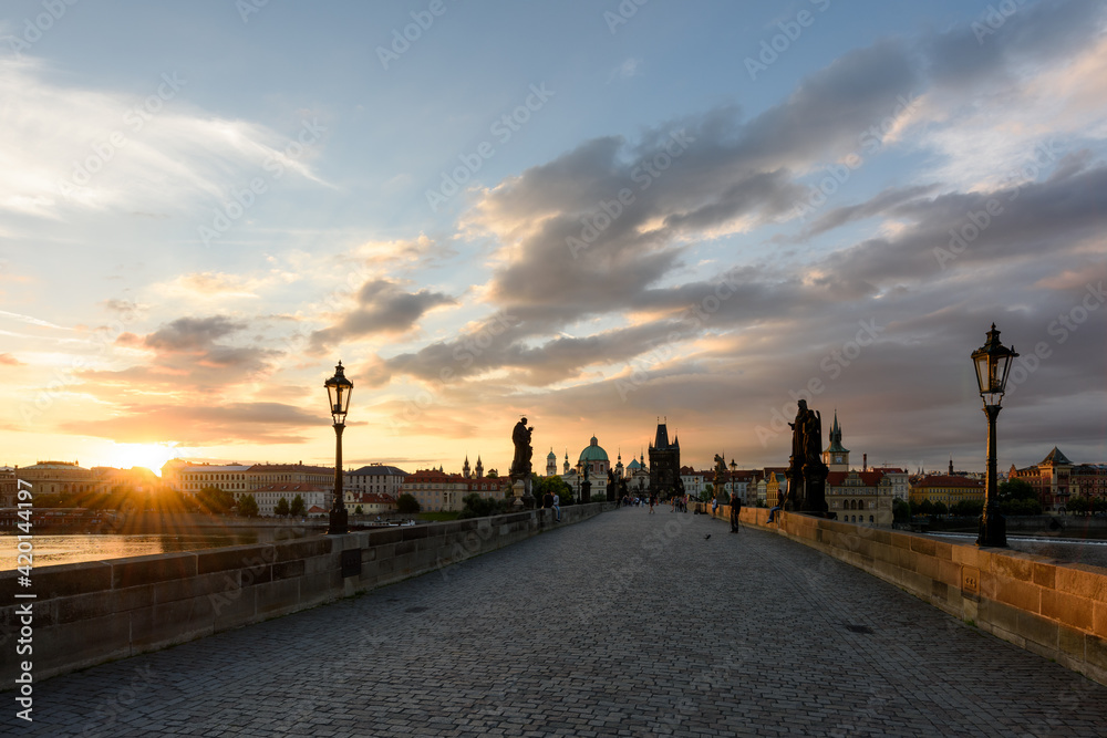 Charles Bridge in the morning at dawn, Old Town of Prague. The sun rises over the Vltava river. Travel in the Czech Republic. Famous tourist places in Europe.