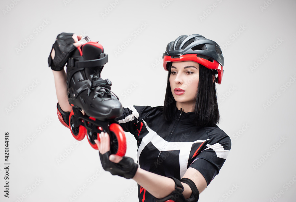 slender woman in sportswear and helmet with roller skates in her hands on a white background slender woman in sportswear and helmet with roller skates in her hands on a white background