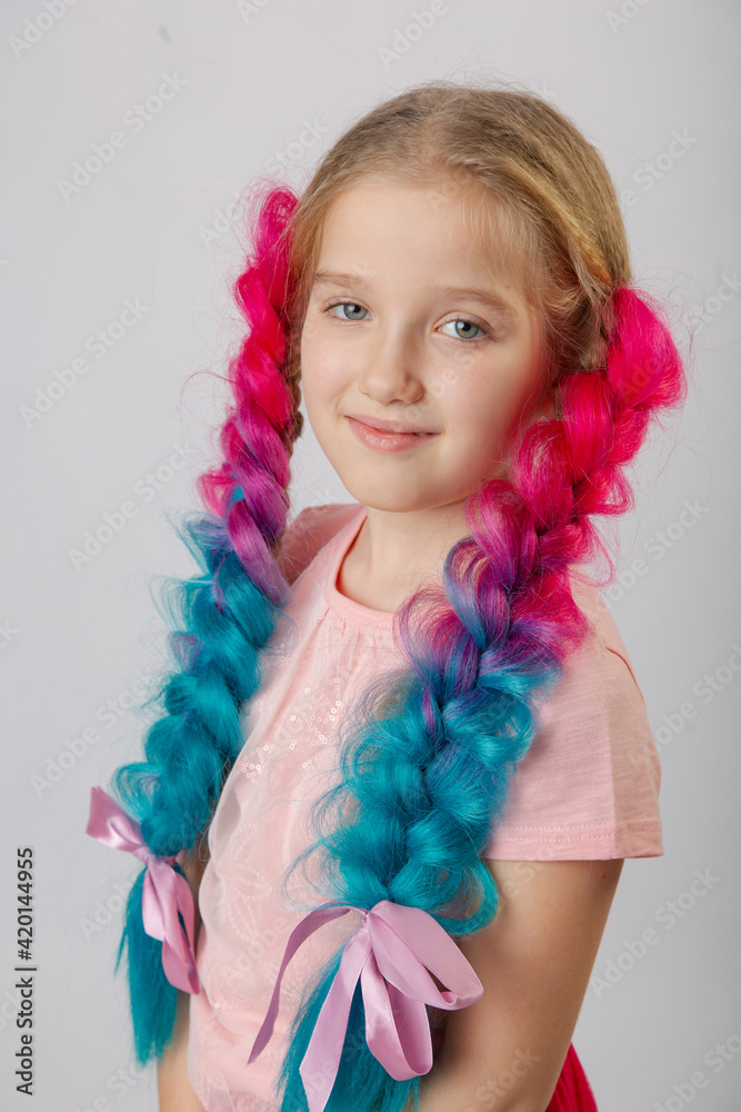 Cute little girl with blond hair and multi-colored bright canecalons with balloons on a light background