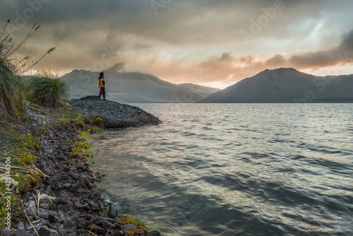 Teenager looking at a cloudy sunset above the Mojanda lake photo