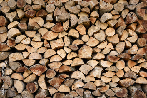 A wall of firewood  a background of dry chopped firewood stacked in several rows. Alternative fuel concept. Firewood for fireplace or stove heating. A wide-angle shot of a natural background.
