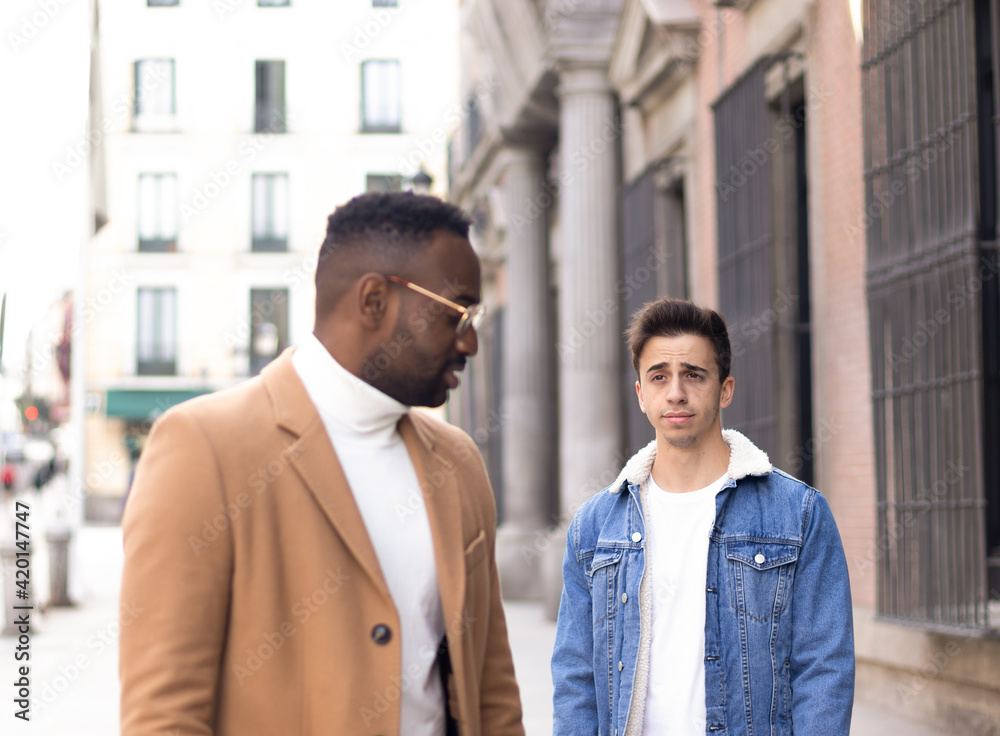 Man looking his friend with pride in the middle of a street. Afro-american and caucasian man. Man looking his friend with pride in the middle of a street. Afro-american and caucasian man.