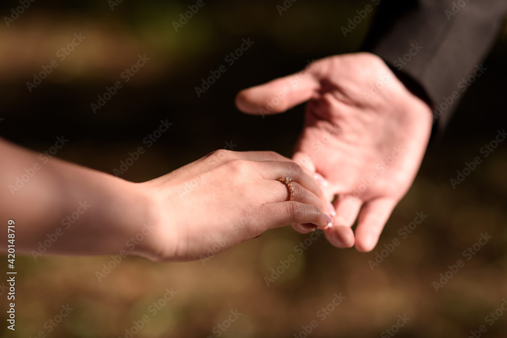 Man holds a woman's hand with a wedding ring or engagement ring on his finger. Close-up of hands. Man holds a woman's hand with a wedding ring or engagement ring on his finger. Close-up of hands.