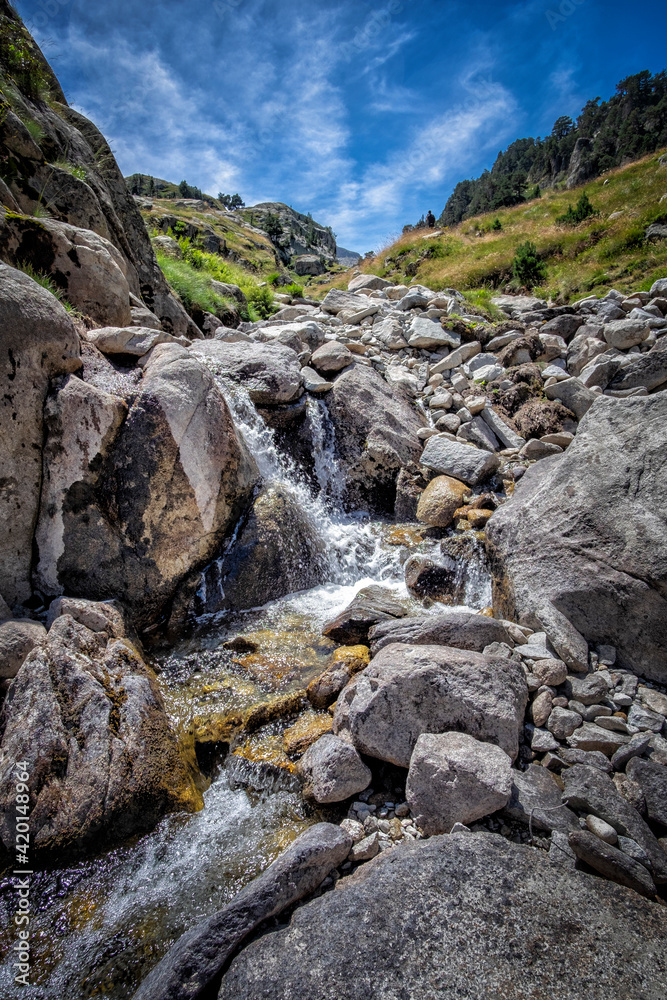 meltwater river flows through a rocky gorge from the top of a mountain, in the natural park of Aiguestortes, in the Catalan Pyrenees of Lerida, Spain meltwater river flows through a rocky gorge from the top of a mountain, in the natural park of Aiguestortes, in the Catalan Pyrenees of Lerida, Spain